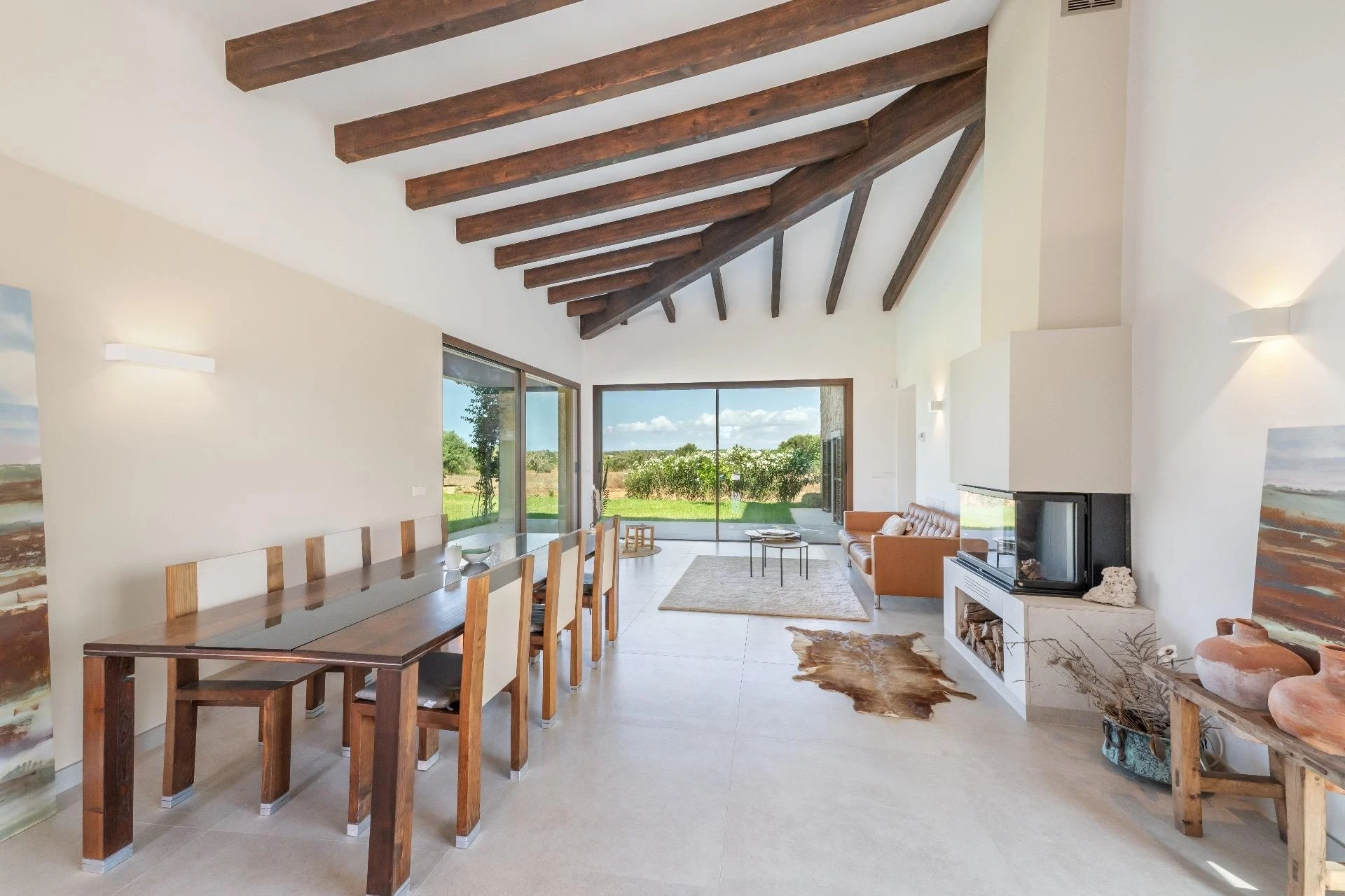Comedor con vigas de madera, chimenea y vistas al jardín — Finca en Ses Salines, Mallorca
