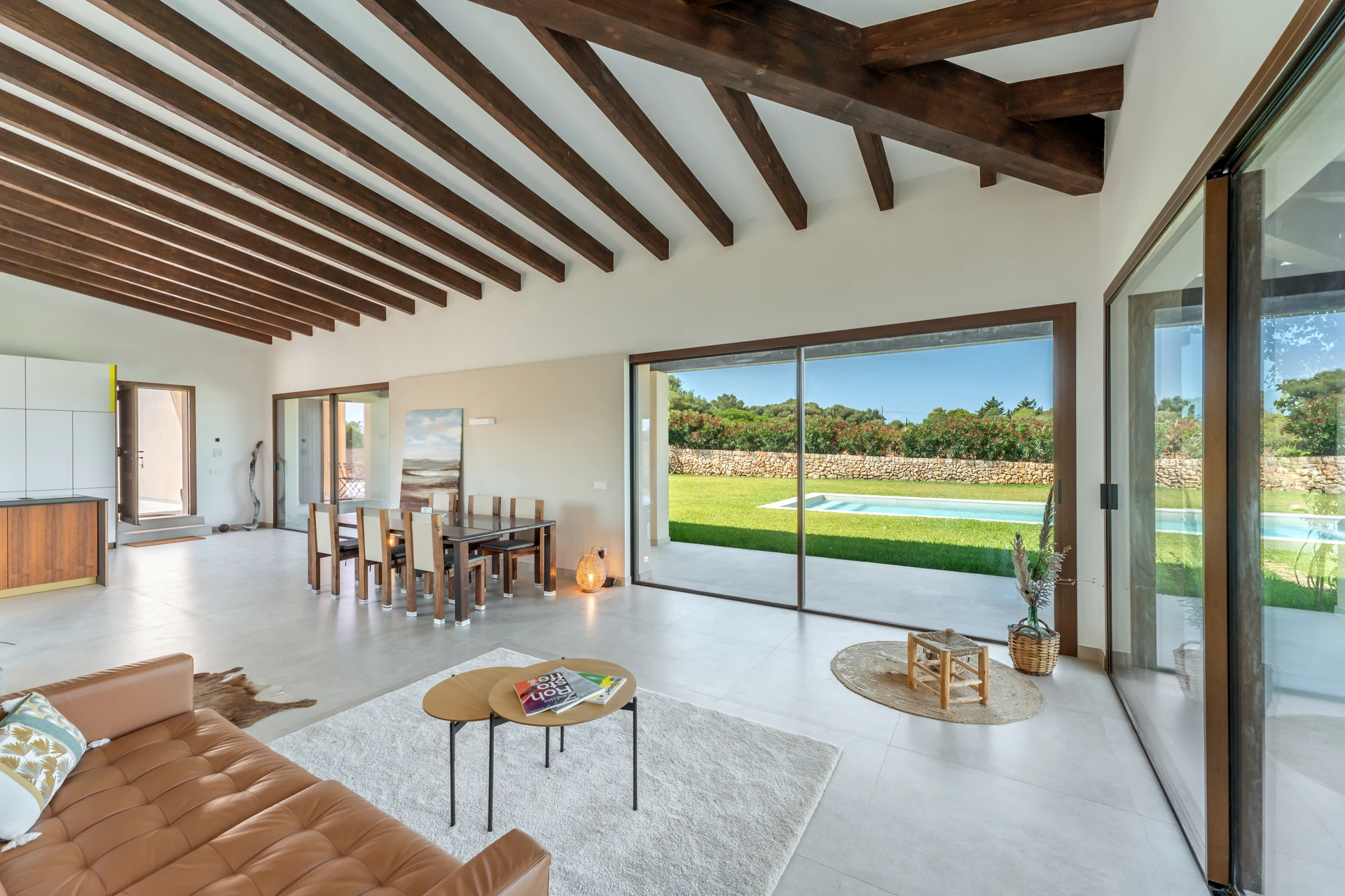 Salón con sofá de cuero, vigas de madera y cristaleras al jardín — Finca en Ses Salines, Mallorca